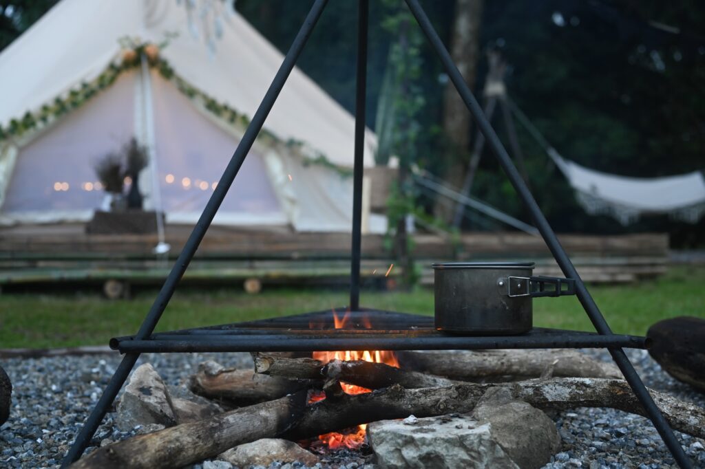 Campfire near camping tent in the forest.